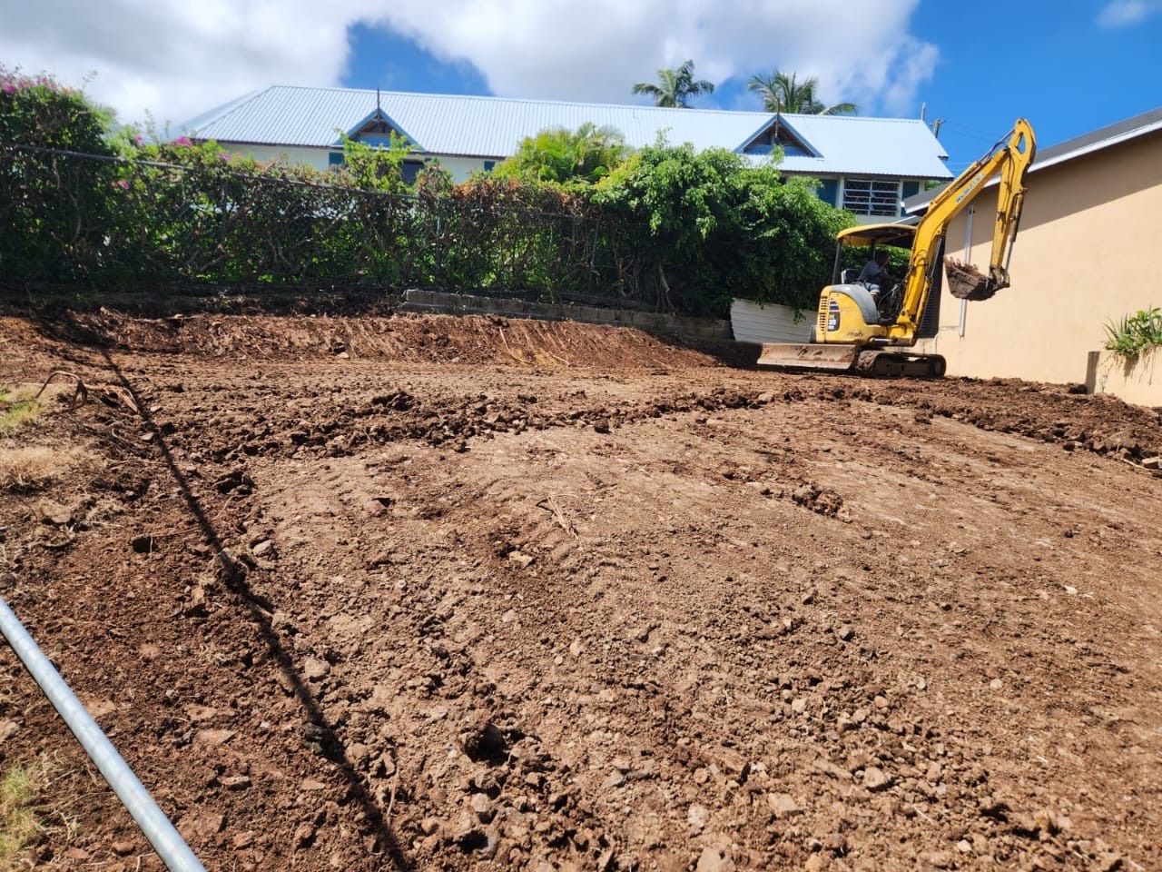 Excavator performing earthworks during site preparation in Saint Lucia with Turf Pro Landscaping.